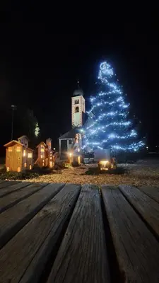 a christmas tree with blue lights in front of a building at Appartamento Casa AleF - L'affaccio sul Lagorai in Daiano