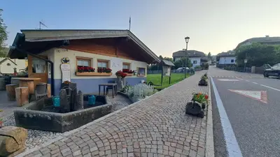 a small building with flowers on the side of a street at Appartamento Casa AleF - L'affaccio sul Lagorai in Daiano