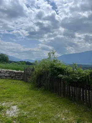 a wooden fence in a field with a stone wall at Grasspeintenhof Reiterhof in Falzes