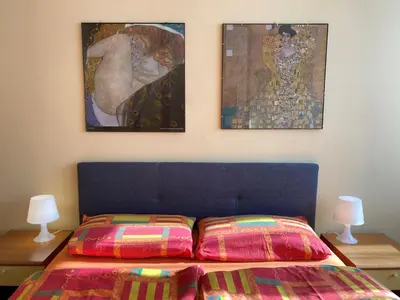a bedroom with a bed with two paintings on the wall at Thermae Apartment in Merano