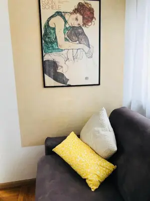 a couch with a yellow pillow sitting under a painting at Thermae Apartment in Merano