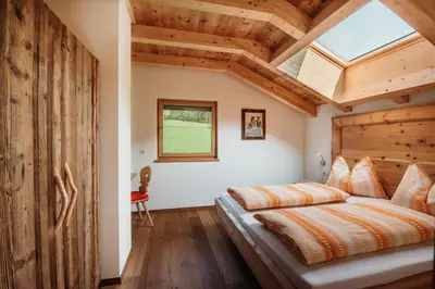 a bedroom with a large bed with a wooden ceiling at Großkarnaiderhof Ferienwohnungen-Bauernhof-Dolomiten-Natur Pur in Luson