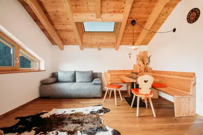 a living room with a table and a couch at Großkarnaiderhof Ferienwohnungen-Bauernhof-Dolomiten-Natur Pur in Luson