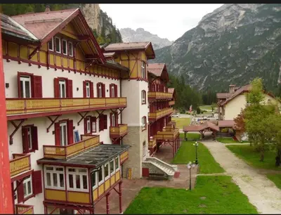 a building with red and yellow trim and a mountain at Chalet con vista villaggio ploner in Dobbiaco