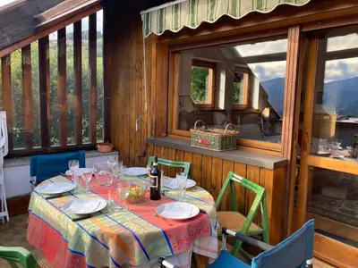 a table with plates and wine glasses on a balcony at Chalet Genziana in Cavalese