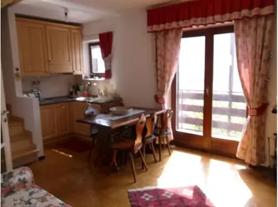 a kitchen with a table and chairs and a kitchen with a window at Moena Appartamento Fior di Melo con WiFi e Riscaldamento in Moena