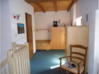 a room with a chair and a room with a bed at Moena Appartamento Fior di Melo con WiFi e Riscaldamento in Moena