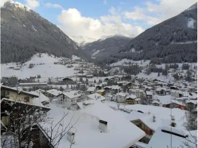 a town covered in snow with mountains in the background at Moena Appartamento Fior di Melo con WiFi e Riscaldamento in Moena