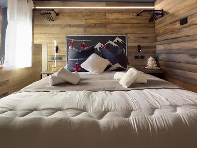 a bedroom with a large white bed with wooden walls at Duo Charme in Moena