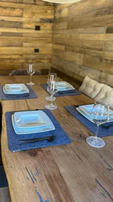 a wooden table with plates and wine glasses on it at Duo Charme in Moena