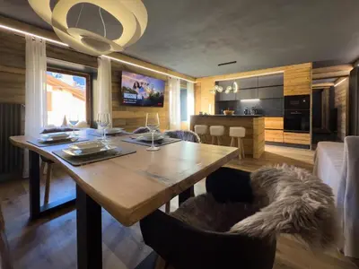 a dining room with a wooden table and a kitchen at Duo Charme in Moena
