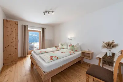 a bedroom with a large bed and a window at Austillerhof - Urlaub auf dem Bauernhof in Funes
