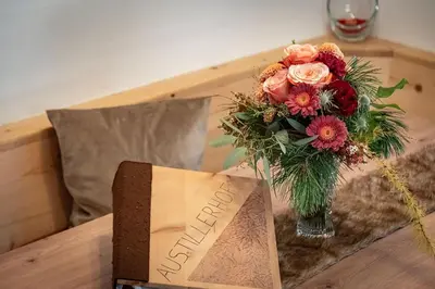 a vase of flowers on a table next to a box at Austillerhof - Urlaub auf dem Bauernhof in Funes