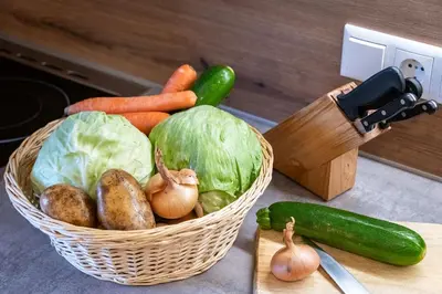 a basket of vegetables on a counter with a knife at Austillerhof - Urlaub auf dem Bauernhof in Funes