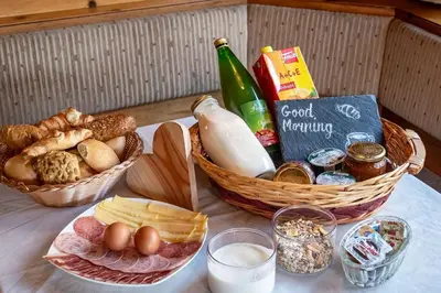 a table with baskets of bread and eggs and milk at Austillerhof - Urlaub auf dem Bauernhof in Funes