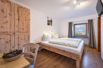 a bedroom with a bed and a table and a window at Austillerhof - Urlaub auf dem Bauernhof in Funes