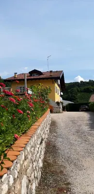 a yellow house with a gate and a garage at Agritur Casa al Mulino Appartamenti in Sanzeno