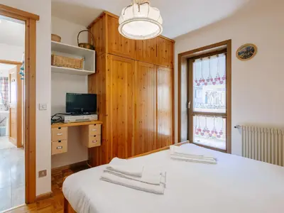 a bedroom with a bed and a desk with a computer at Apartment Fontanelle-3 by Interhome in Alba di Canazei