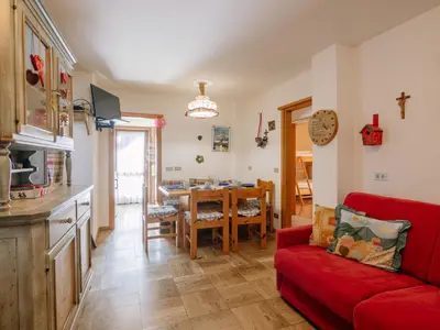 a living room with a red couch and a dining room at Apartment Fontanelle-3 by Interhome in Alba di Canazei
