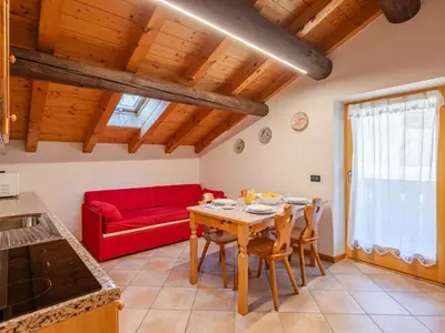 a living room with a table and a red couch at Apartment Casa Costazzer B by Interhome in Mazzin