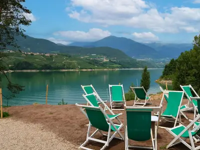a row of chairs sitting next to a lake at Apartment Elisa by Interhome in Ronzone