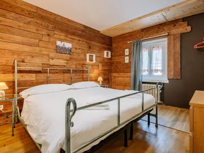 a bedroom with a bed in a room with wooden walls at Apartment Cesa Giordi by Interhome in Canazei