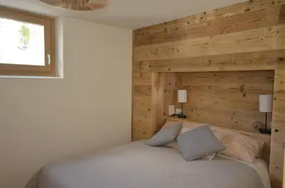 a bedroom with a bed with a wooden wall at Dolomiti charme in Cortina dʼAmpezzo