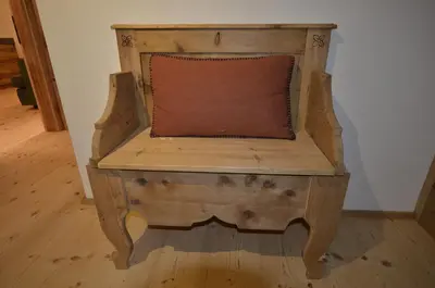 a wooden chair with a pillow on top of it at Dolomiti charme in Cortina dʼAmpezzo