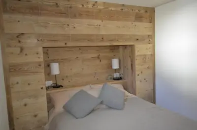 a bedroom with wooden walls and a bed with two pillows at Dolomiti charme in Cortina dʼAmpezzo