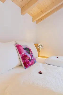 a white bed with a pink pillow on top of it at Wibmerhof in Tesido