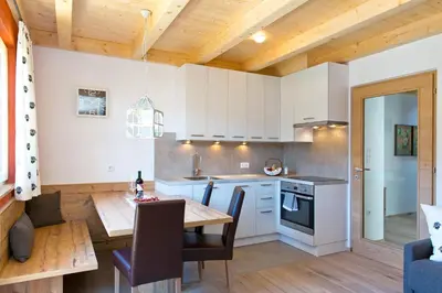a kitchen with white cabinets and a wooden ceiling at Wibmerhof in Tesido