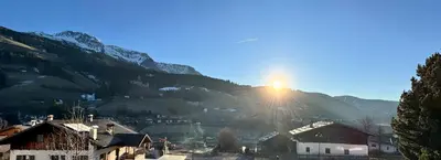 a sun setting on a mountain with a village at Apartment Rohrer - Zirm - Zirbe Cirmolo mit Schloss- und Schourtblick in Sarntal