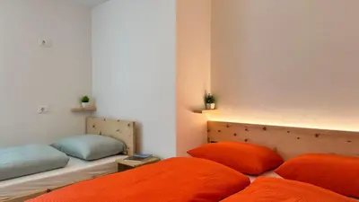 two beds with orange pillows in a room at Apartment Rohrer - Zirm - Zirbe Cirmolo mit Schloss- und Schourtblick in Sarntal