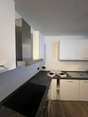a kitchen with white cabinets and a black counter top at Cèsa Sot Bosch in Canazei