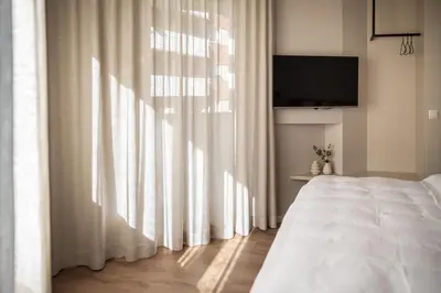 a bedroom with a bed and a window with curtains at Avista Apartments Terme in Merano