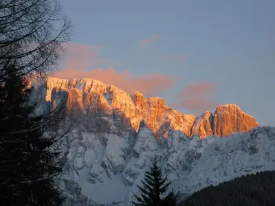 a snow covered mountain with the sun shining on it at Le Ginestre in Alleghe
