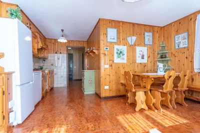 a kitchen with wooden walls and a table and chairs at Le Ginestre in Alleghe