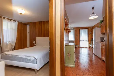 a bedroom with a white bed and a kitchen at Le Ginestre in Alleghe
