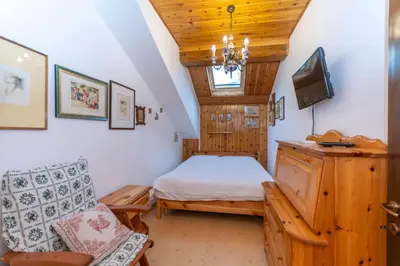 a bedroom with a bed and a tv and a chair at Le Ginestre in Alleghe