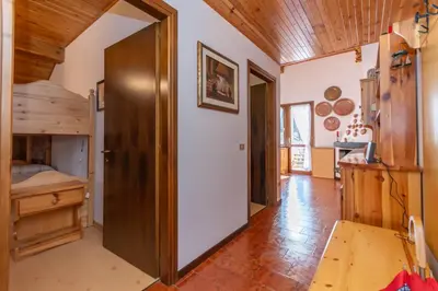 a large room with a door to a kitchen with wooden ceilings at Le Ginestre in Alleghe