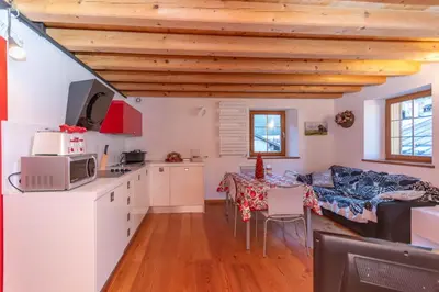 a kitchen and living room with white cabinets and a table at Appartamento Tre Valli 5 in Alleghe