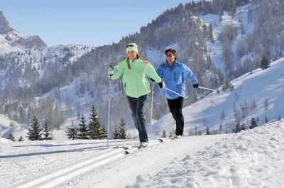 a man and a woman skiing down a snow covered slope at Appartamento Tre Valli 5 in Alleghe