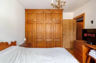 a bedroom with a bed and a wooden cabinet at Dolce Casa Cortina Centro-Ski in Cortina dʼAmpezzo