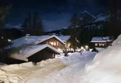 a house is covered in snow at night at APARTMENT - Ski in&out-accesso diretto alle piste in Cortina dʼAmpezzo