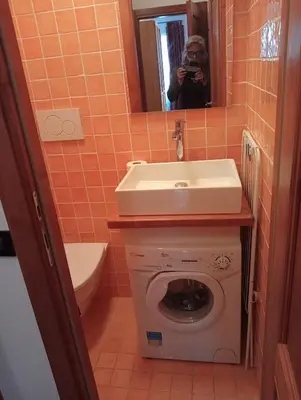 a woman taking a picture of a bathroom with a washing machine and sink at Ca' Ravagnan in Cortina dʼAmpezzo