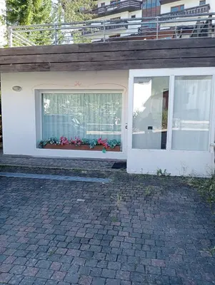 a white house with a window with flowers in it at Ca' Ravagnan in Cortina dʼAmpezzo