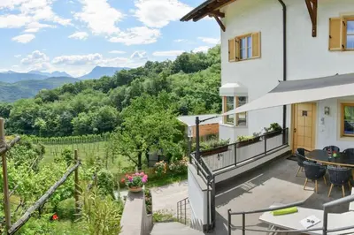 a house with a balcony with a table and chairs at Apartment Seenah in Caldaro