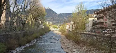 a river in a city with a mountain in the background at Manzoni 99 in Merano