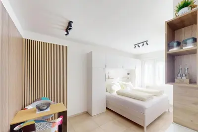 a white bedroom with a bed and a table at Manzoni 99 in Merano