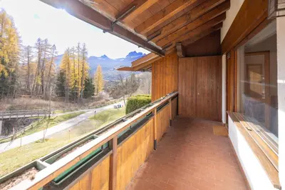 a house with a balcony with a view of the mountains at Casa Funivia, immersa nel verde e vicina al centro di Cortina in Cortina dʼAmpezzo